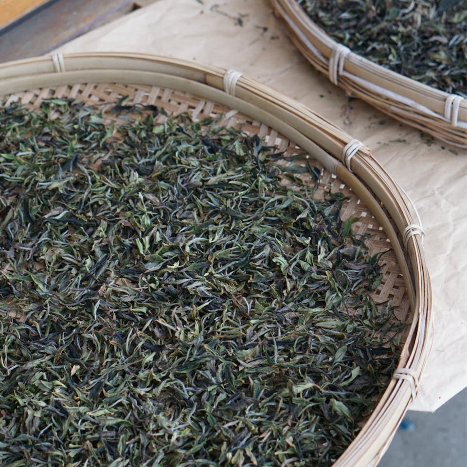 Tea leaves drying in bamboo container